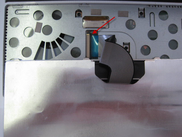 The keyboard is connected using a ribbon. To detach the ribbon from the laptop gently lift the brown retaining clip.