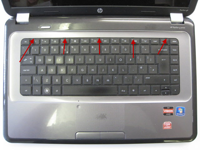 Turn laptop over and remove keyboard. The arrows point to small clips that hold in keyboard which need pushing back